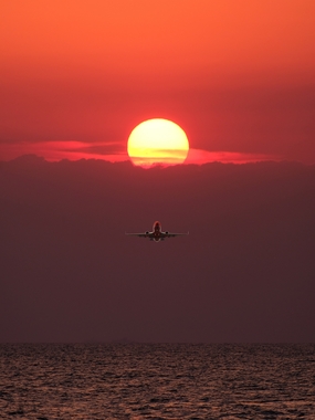 黄昏落日余晖海面飞行的飞机图片